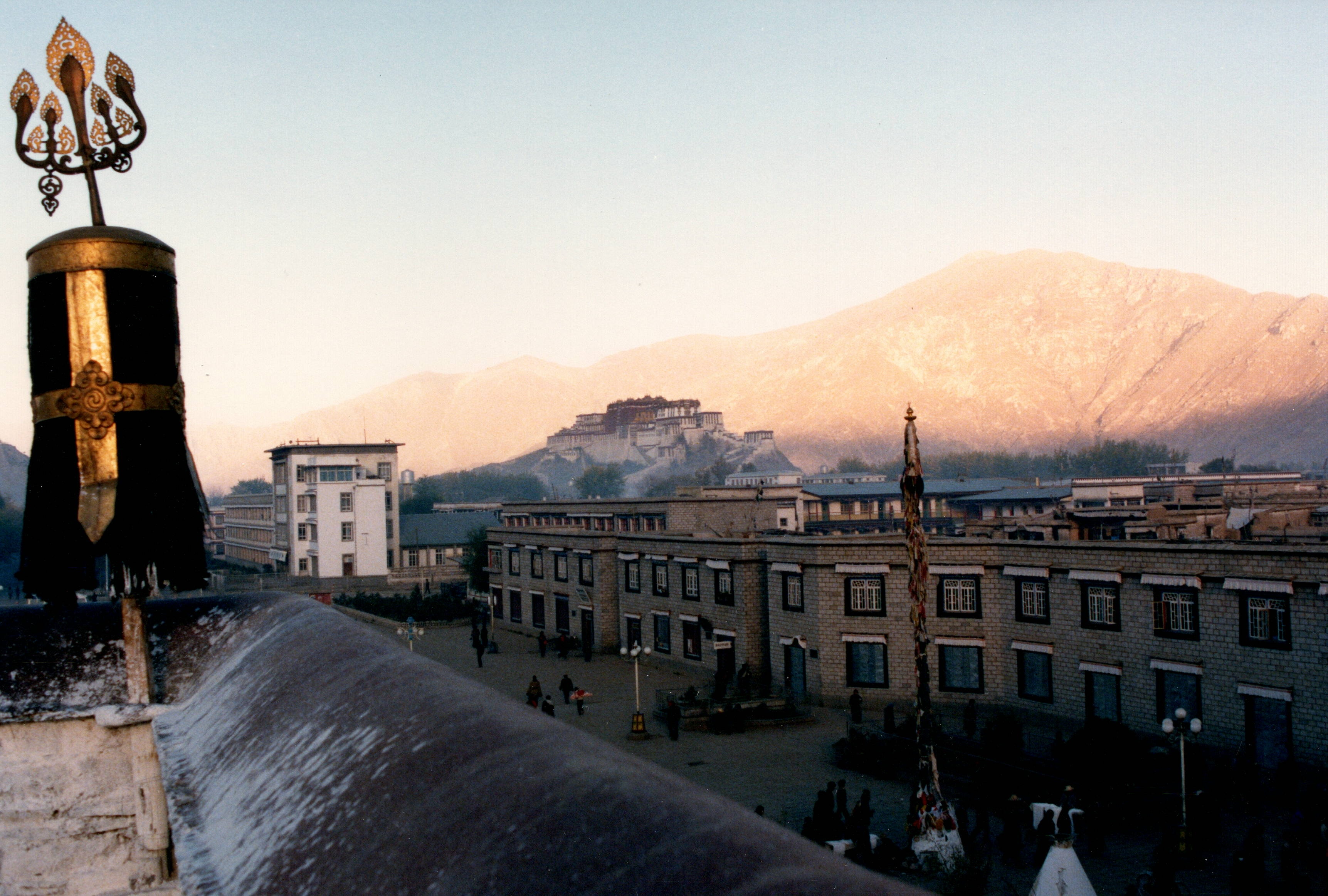 View from a Lhasa rooftop toward the Potala Palace at dusk, mountains behind